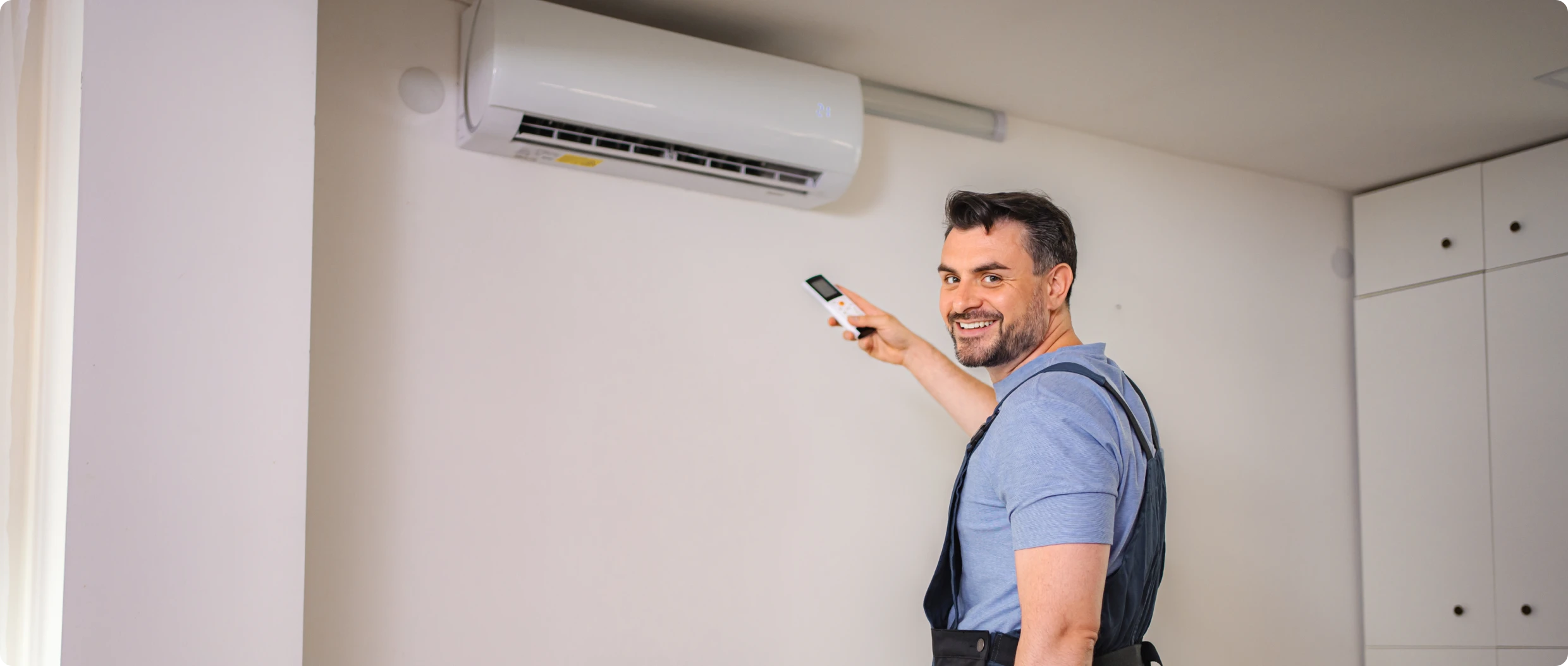Technician operating wall-mounted air conditioning unit